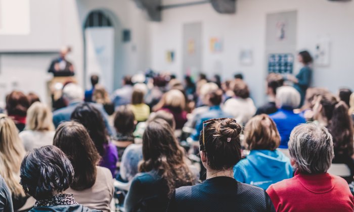 La nuca de decenas de personas que asisten a una presentación en una convención.