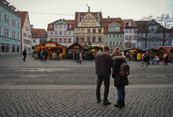  A couple in winter jackets looks at a phone for information while traveling in a foreign country.