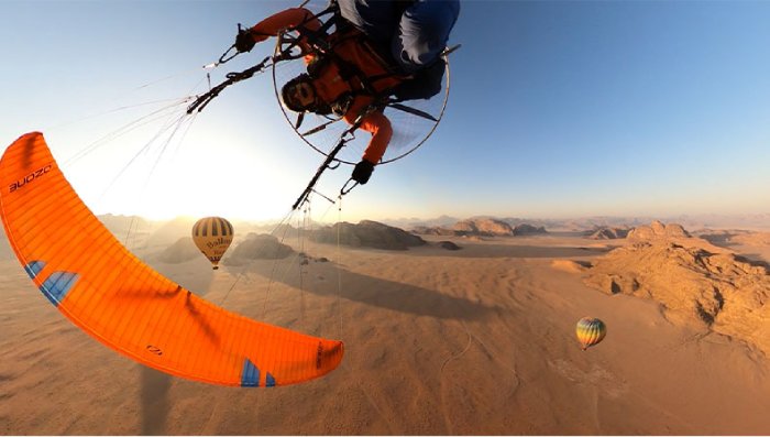 A woman paragliding upside down high above the desert.