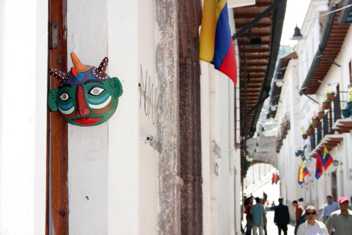 A mask hangs outside a door in a narrow street in Quito, Ecuador.