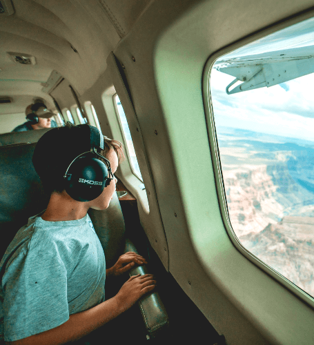 child looking out airplane window flying over the grand canyon