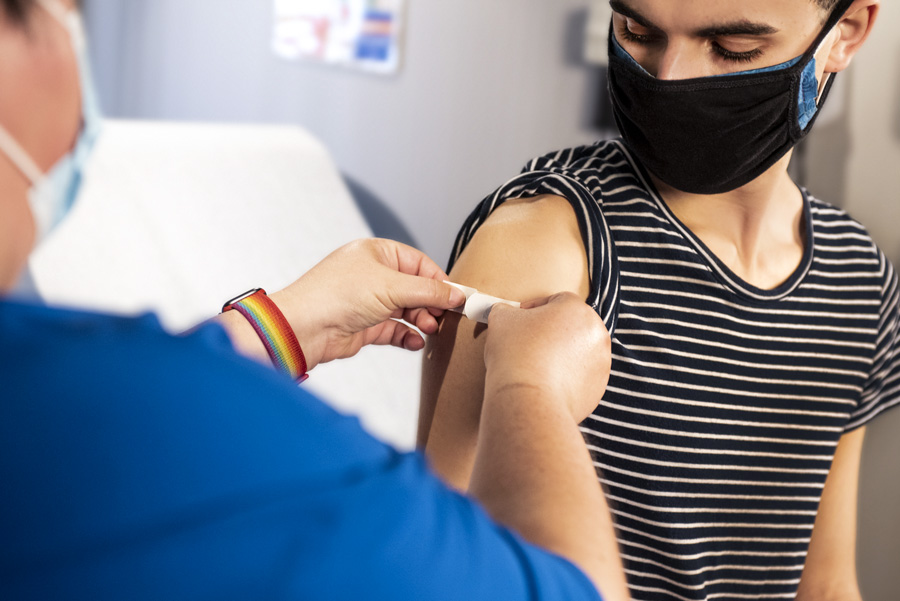 masked young person receiving a vaccine in a doctors office