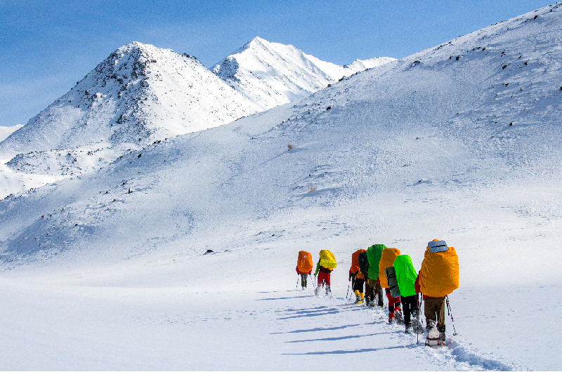 Varios alpinistas de colores atraviesan una montaña nevada.