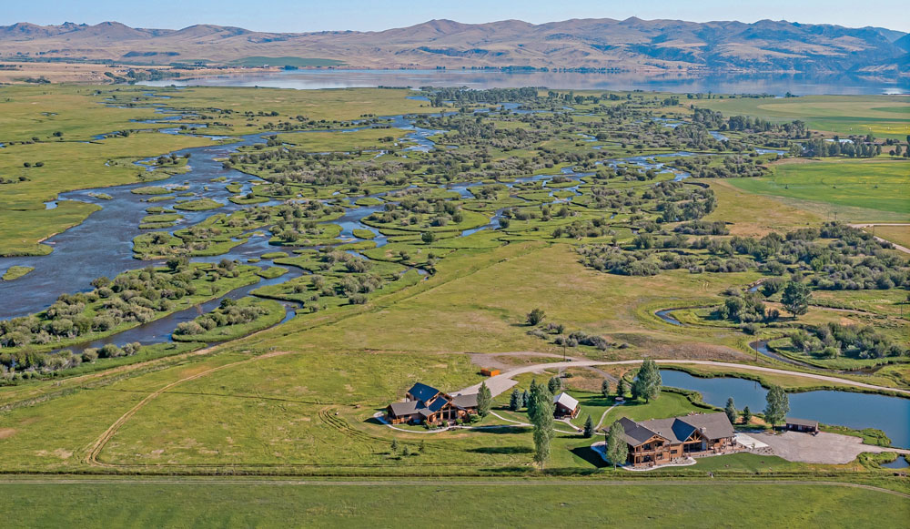 A view from above of the river, grasslands, and far off mountains surrounding the Madison Valley Ranch in Ennis, Montana.