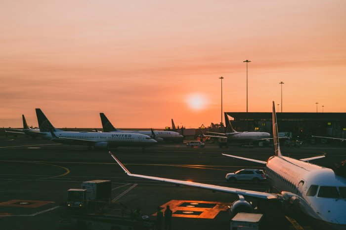 Commercial airplanes wait at their gates at an airport during sunset.