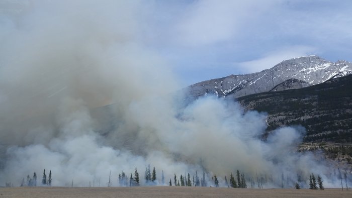 Smoke from mountain wildfires billows into the air during the day.