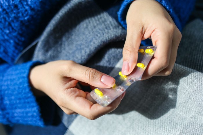 A person popping out yellow pills from their wrappers.