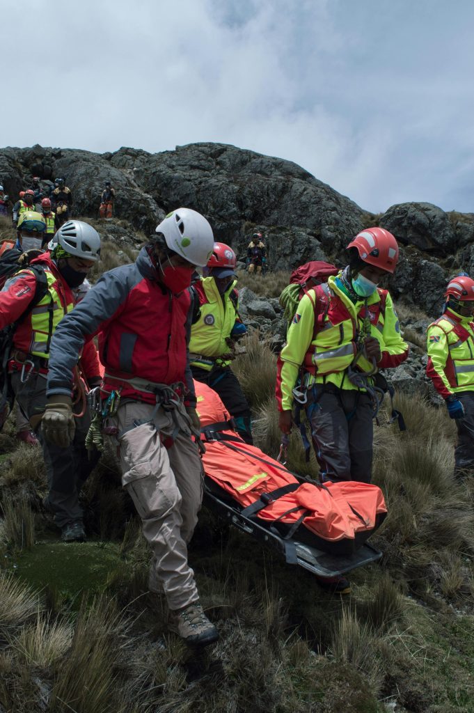 Equipo de rescate transportando a un herido en camilla durante una evacuación en montaña.