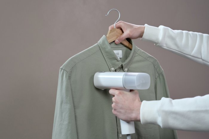 A small clothing steamer working on a green shirt.