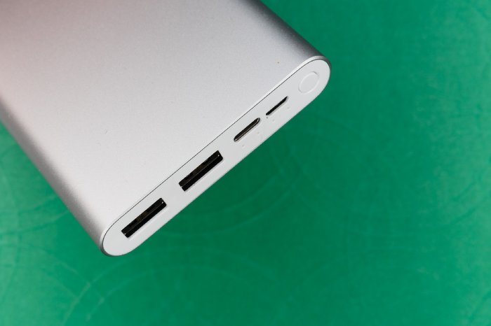 A white portable phone charger on a green background.