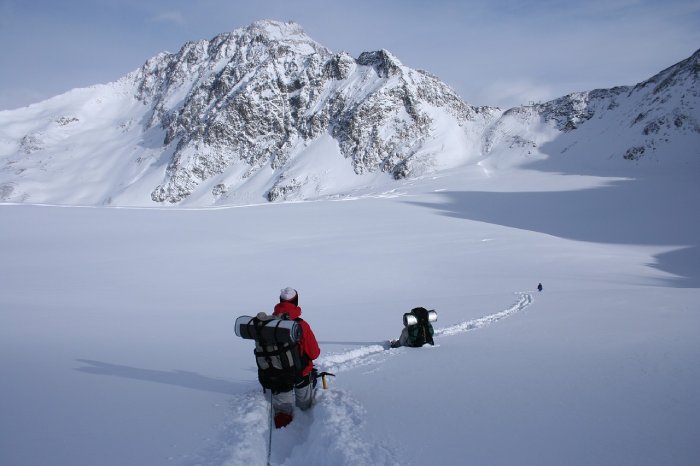 Three winter hikers make descend a mountain in an expanse of deep snow.